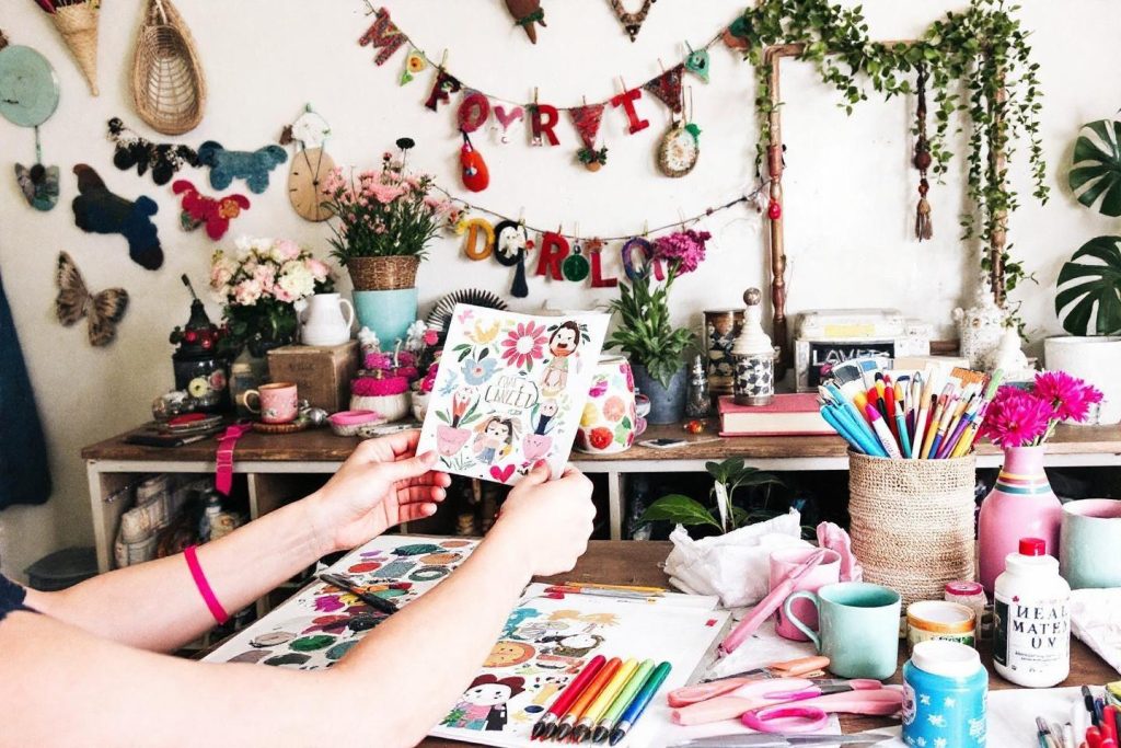 Bureau d'artiste avec matériel de dessin, fleurs et décorations lumineuses