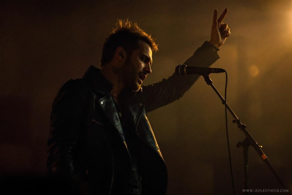 Musicien sur scène, micro, lumière chaude, geste expressif